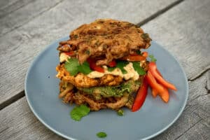 photo of Chicken Tikka Burger between two onion bhajis on a plate