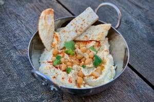 photo of Smoked chickpea hummus in a small metal bowl on a table