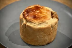 Photo of a cooked Chicken and ham pie on a plate