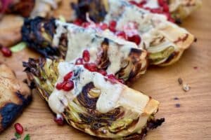 photo of charred Hispi Cabbage with Pomegranate and Tahini sliced on a baord