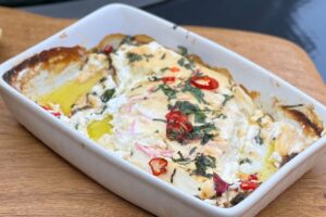 photo of Baked feta in a white oblong dish on a board