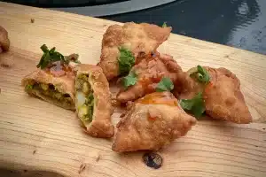 photo of several pea and potato samosas on a board