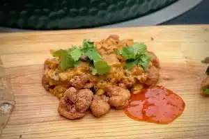 a photo of Chicken 65 garnished with coriander on a board