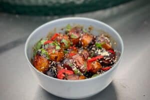 phot of Sticky and Spicy Mini Roasties in a grey bowl next to the bbq
