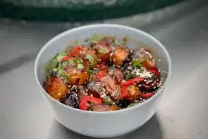phot of Sticky and Spicy Mini Roasties in a grey bowl next to the bbq