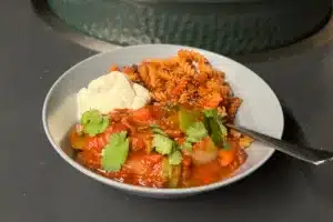 photo of vegetable chilli with pasta fries in a grey bowl next to a bbq