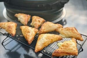 A photo of Cheese and onion puff pasties in front of the Big Green Egg they were cooked on.